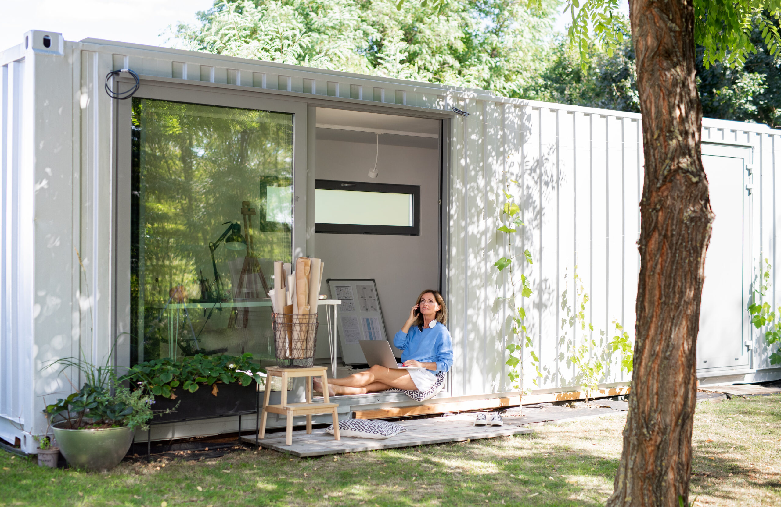 Happy mature woman working in home office in container house in backyard.